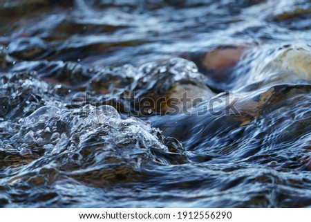 Closeup of Gurgling Water over Cobblestone in a River Royalty-Free Stock Photo #1912556290