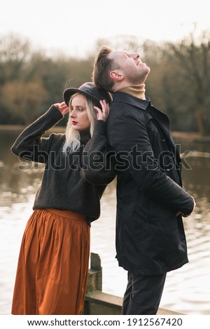 man and woman standing back each other, background lake