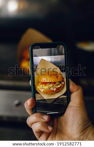 
hand with phone and burger photo