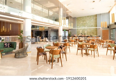 Light wooden and marble tile floor interior of modern cafe with double ceiling height. Lobby bar in luxury design hotel hall with second split level Royalty-Free Stock Photo #1912600201