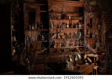 Halloween background Shelves with alchemy tools Skull spiderweb bottle with poison candles Witcher workspace Scarry room Royalty-Free Stock Photo #1912601095