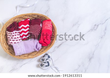 Odd sacks day, multi-colored socks twisted into one another in a woven straw basket.
