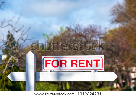 For Rent real estate sign. Blurred sky and trees background.