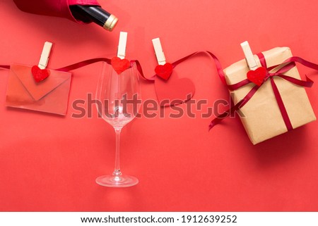 Romantic background, red heart and envelope, glass and a gift box, happy holiday on February 14, dating and love concept, copy free space.
Romantic decorations hanging  on thread against wooden plank.