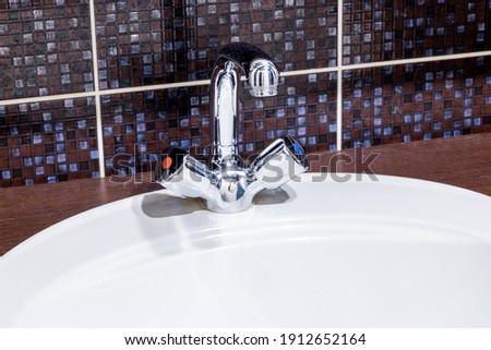 chrome faucet and white ceramic sink close up at domestic bathroom. apartment bathroom interior.
