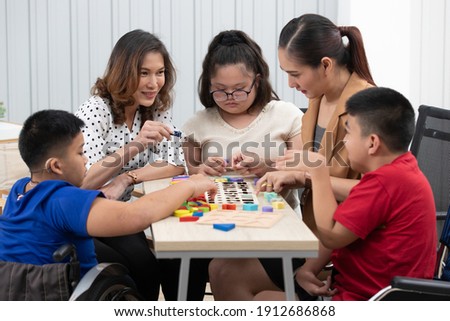 Group of special students in classroom, a down syndrome girl, two handicapped boys and cute Asian teacher playing toy and game together. Royalty-Free Stock Photo #1912686868