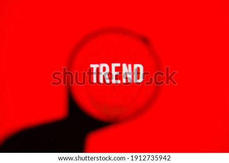 Text trend on red screen through magnifying glass.