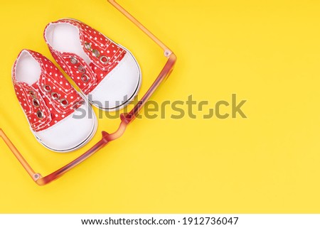 children's shoes with white polka dots with red glasses on a yellow background