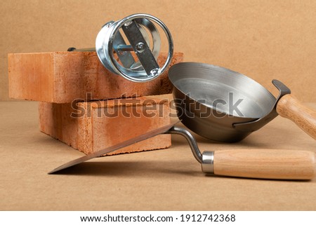 Picture of brick and mason tools on wooden background, top view