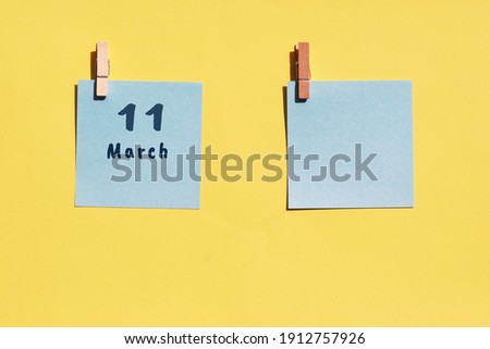 March 11st. Day of 11 month, calendar date. Two blue sheets for writing on a yellow background. Top view, copy space. Spring month, day of the year concept