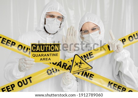 Epidemiologists a man and a woman in protective clothing are in a restricted area with a danger sign. Coronavirus, covid-19.
