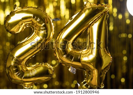 Golden number 24 twenty four made from an inflatable balloon, on a yellow background. One of the complete set of numbers. The concept of birthday, anniversary, date