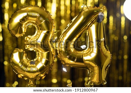 The golden number 34 thirty four is made of an inflatable balloon on a yellow background. One of the complete set of numbers. Birthday, anniversary, date concept