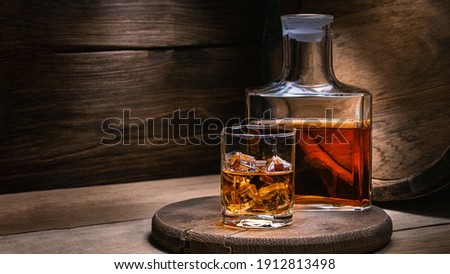 Whiskey drinks. You need to drink whiskey with ice then the whiskey tastes better of an oak barrel. Alcoholic drink with ice whiskey or cognac close-up on an oak coaster for glasses for spirits. Royalty-Free Stock Photo #1912813498