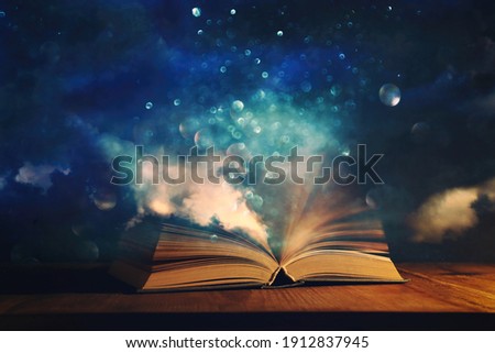 Magical image of open antique book over wooden table with glitter overlay Royalty-Free Stock Photo #1912837945