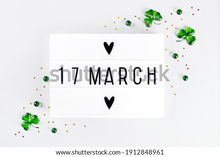 Lightbox with 17 march text Saint Patricks day greeting green hearts shamrock symbols and gold stars confetti on white background. Flat lay Irish holiday party card Spring 17 march lucky clover design