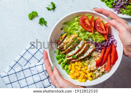 Grilled chicken breast with brown rice and vegetables in a white plate, gray background. Healthy food concept. Royalty-Free Stock Photo #1912852510