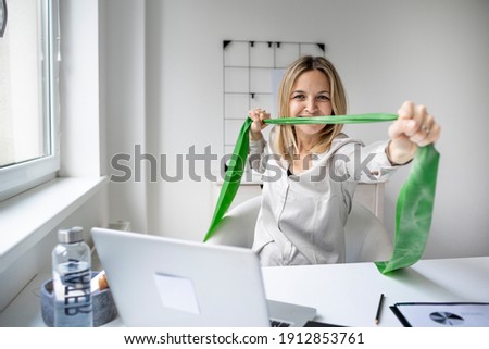 Business woman working and doing sport in her office with fitness band
