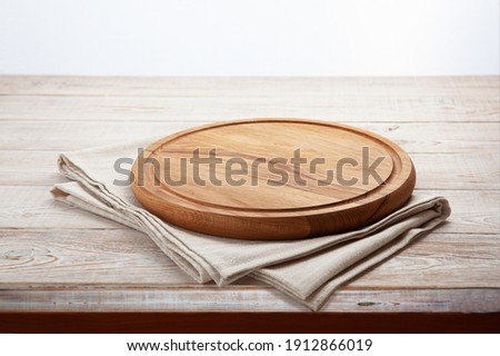 Empty pizza board and canvas tablecloth on white wooden deck. Selective focus. Royalty-Free Stock Photo #1912866019