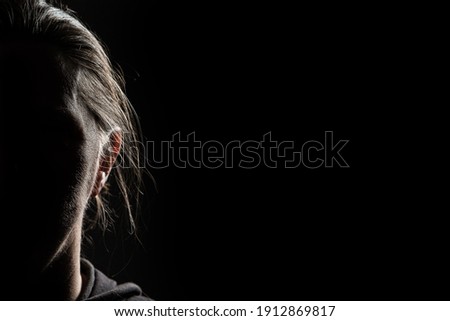 Half face of unrecognizable woman in shadow shrouded in darkness isolated on black background with wide copy space, concept of anonymity to hide one's identity, women who have suffered violence Royalty-Free Stock Photo #1912869817