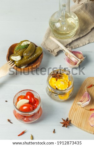 Fermented vegetables, home canning. Tomatoes, squash and cucumbers in a marinade with spices. Close-up on a light wooden background