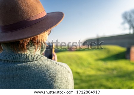 Beautiful cheerful adult woman in felt hat and sweater making selfie on smartphone sunny spring day