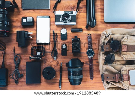 Top view digital camera,film camera, charger, camera, lens, video camera, USB, personal laptop, book, glasses, remote control, electronics camera accessory photography concept on wooden background Royalty-Free Stock Photo #1912885489