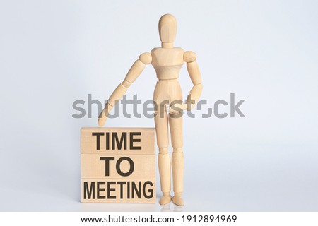 Wooden man shows with a hand text TIME TO MEETING concept on wooden block