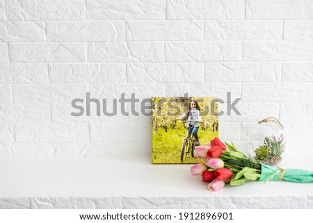 photo canvases of active little girl and flowers tulips as a holiday gift lie on the shelf