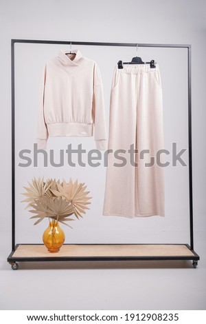 Beige womens jersey suit, sweatshirt, palazzo pants. Rack with stylish women's clothes isolated on white. High quality photo