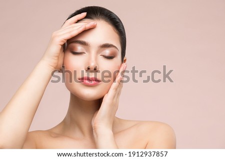 Beautiful Woman Face Skin Care. Natural Make up. Skin Health Treatment. Model massaging Face by Hands. Beige background Royalty-Free Stock Photo #1912937857