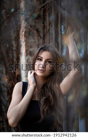 beautiful smiling woman with long hair and black dress in a garden