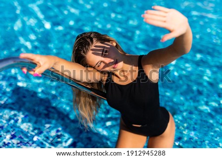 Beautiful woman entering swimming pool in bikini