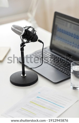 post production, podcast and technology concept - microphone and sound editor program on laptop computer at office