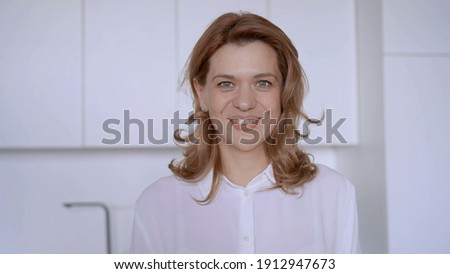 Businesswoman stands in a modern kitchen and smiles. High quality photo