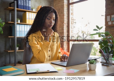 Photo of thoughtful dark skin woman browse internet laptop on table think business plan wear yellow shirt indoors in office Royalty-Free Stock Photo #1912957819