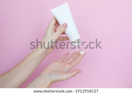 
Woman's hands with a tube and a swatch of cream on a pink background. Cosmetic products concept. Copy space Royalty-Free Stock Photo #1912958527