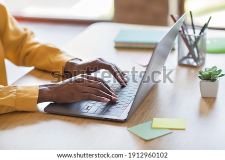 Cropped photo portrait of african american woman's hands typing on laptop in modern office indoors Royalty-Free Stock Photo #1912960102