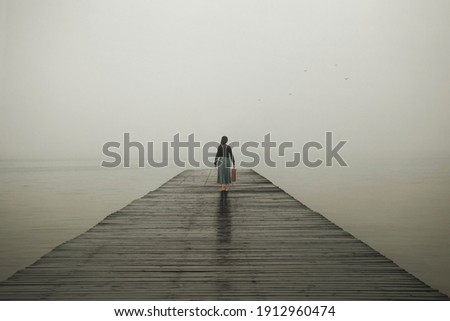 woman with suitcase walks towards her destiny  Royalty-Free Stock Photo #1912960474