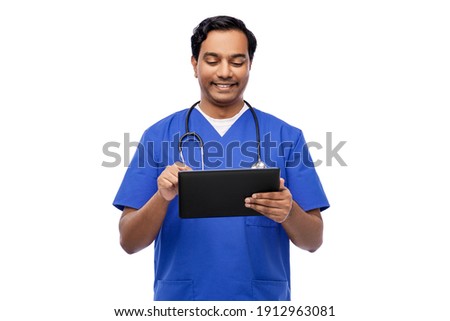 medicine, healthcare and technology concept - happy smiling indian doctor or male nurse in blue uniform with stethoscope using tablet pc computer over white background