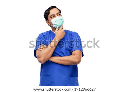 healthcare, profession and medicine concept - thinking indian doctor or male nurse in blue uniform and face protective medical mask for protection from virus disease over white background