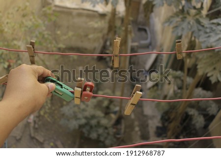 Human hand want to pick up the clothes pins. Rows of clothes pins to hold dry clothes. clothespins and the line in the balcon apartemen. With green, red and brown color clothes pins.