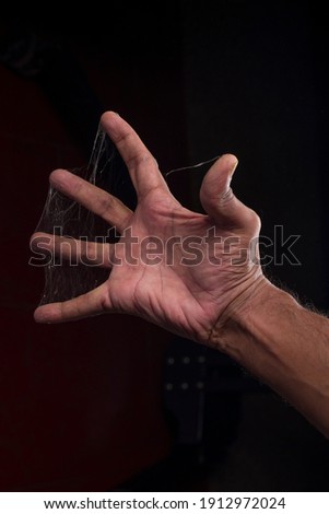 A man fingers covered with spider web on black background
