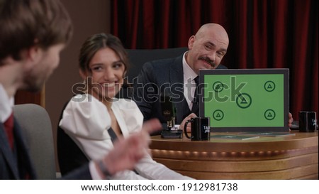 Late-night talk show host showing a green board with tracking points to celebrity guests in a studio. TV broadcast style show 