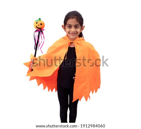Cute little girl dressed in pumpkin costume holding a magic wand  on white background for Halloween .