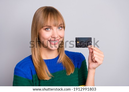 Photo portrait of young woman showing bank credit card smiling isolated on pastel grey color background