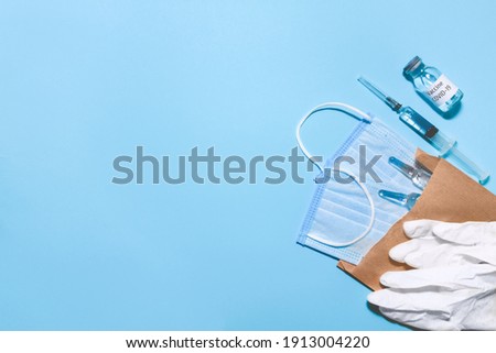 Vaccination concept. Top view, flat lay, copy space. Syringe and vaccine vial glass bottle for vaccination against COVID-19 SARS-CoV-2 coronavirus pandemic, medical gloves lying with surgical masks.  Royalty-Free Stock Photo #1913004220