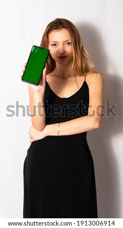 young woman holding a green screen phone.