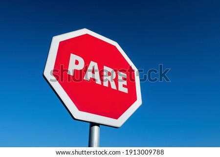 Traffic sign with the word STOP translated to English (PARE in Spanish and Portuguese) in perspective view against blue sky