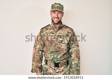 Young caucasian man wearing camouflage army uniform with a happy and cool smile on face. lucky person. 
